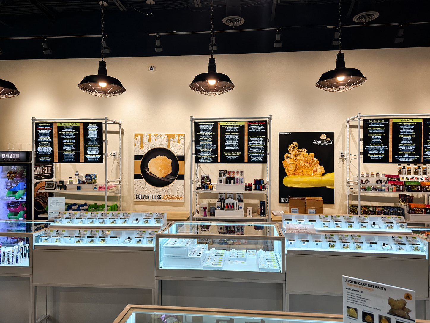 Inside an Apothecary Farms dispensary with product display cases and Apothecary Extracts menu boards
